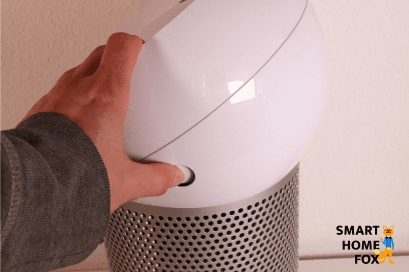 Um den oberen Teil des Dyson Pure Cool Me BP01 Luftreinigers abzunehmen, muss man die seitlichen Knöpfe eindrücken